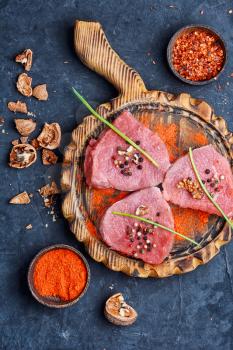 Raw beef steak with spices and walnuts on the kitchen board