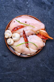 chicken raw fillets on kitchen plate with pepper and onions.Copy space