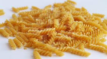 Spill spiral pasta on white background. Raw uncooked food macaroni