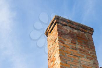 Old red brick chimney on blue clear sky background