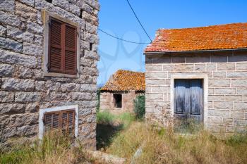 Figari, South Corsica, rural architecture example. Old living houses made of stones with red tile roofs, wooden doors and windows