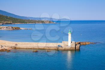 White lighthouse tower on stone pier. Entrance to Propriano port, Corsica, France