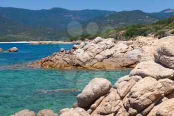 Corsica island, wild coastal landscape with stones in blue sea water. Selective focus on a foreground