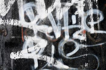 Abstract urban background texture: old black painted metal wall with a graffiti on it