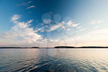 Coastline of Saimaa lake with clouds reflected on still water