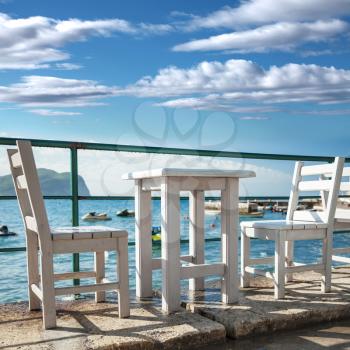 White wooden chairs and table stand on the Adriatic sea coast