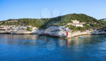Cliffs with old building and red lighthouse, entrance to the port of Bonifacio, Corsica island, France