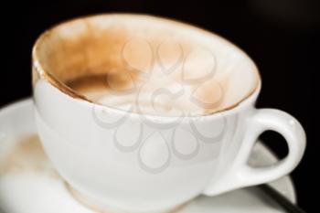 Half cup of cappuccino. Coffee with milk foam in white mug over black background