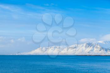 Icelandic coastal landscape with white snowy mountains under blue sky. Reykjavik area, Iceland