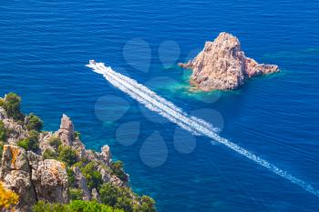 Fast motor boat goes near rocks of Capo Rosso, Piana region, South Corsica, France
