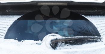 Car wiper on rear SUV window covered with snow in cold winter season
