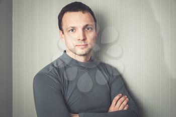 Studio portrait of young serious European man in gray sportswear