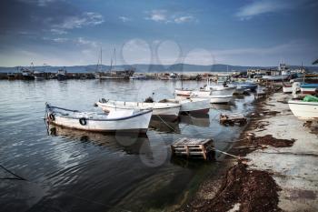 White wooden fishing boats are moored in port of old Nesebar town, Burgas, Bulgaria. Vintage blue tonal correction filter, retro style effect