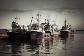 Industrial fishing boats are moored in port of old Nesebar town, Burgas, Bulgaria. Vintage tonal correction filter, retro style effect