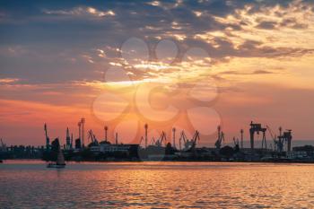 Varna port under dramatic cloudy sky at sunset. Black silhouettes of cranes and ships