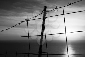 Barbed wire fence with sea on a background. Black and white landscape of Zakynthos
