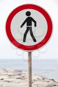 Entry prohibited sign stands on a coastal breakwater structure, vertical photo