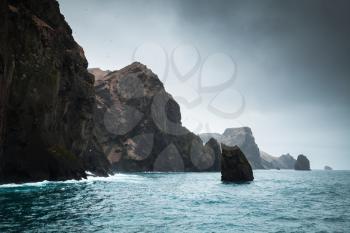 Rocky coast of Vestmannaeyjar island in dark cloudy day, Iceland