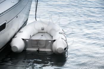 Small white inflatable boat floating near a yacht