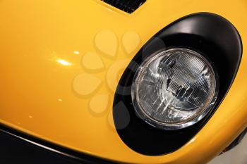 Yellow luxury vintage sport car headlight, close-up photo with selective focus
