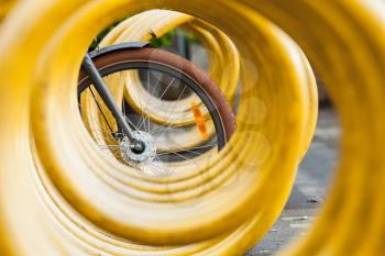 Bike wheel and yellow spiral bicycle parking lot stand