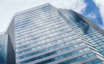 Abstract modern architecture background photo, office tower made of glass and steel with reflections of cloudy sky
