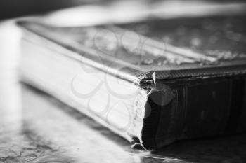 Closed vintage book lays on wooden table, close up photo with selective focus
