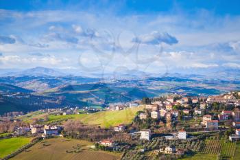 Panoramic landscape of Italian countryside. Province of Fermo, Italy. Village on hills under blue cloudy sky
