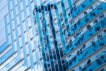Modern architecture style. Abstract fragment, walls made of glass and steel with reflections of blue sky
