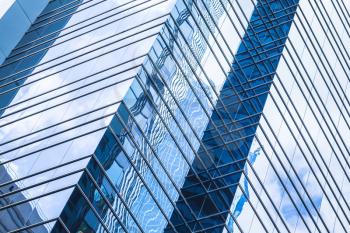 Modern business architecture, abstract fragment, walls made of glass and steel with reflections of blue sky