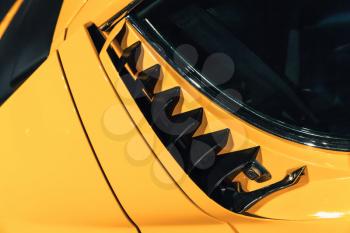 Luxury yellow vintage roadster fragment, aerodynamics air intake grille on a car bonnet