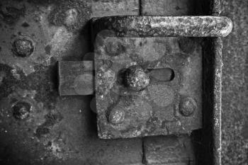 Old rusted lock on dark steel door, black and white photo