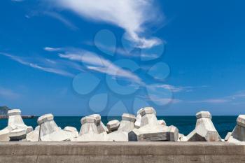Breakwater structure with concrete blocks under cloudy sky. Industrial background photo