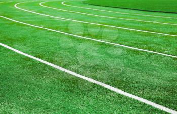 Empty running track with bright green artificial turf and lines