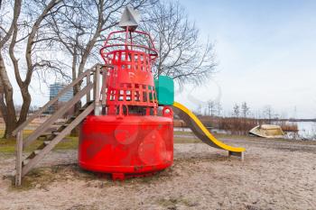 Slide made of red navigation buoy on public playground of Muiderzand marina, Amsterdam, Netherlands