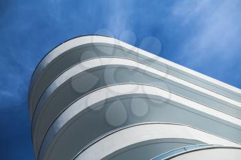 Abstract modern architecture fragment, round white concrete facade under blue cloudy sky