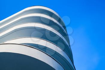 Abstract modern architecture fragment, round white concrete facade under bright blue sky