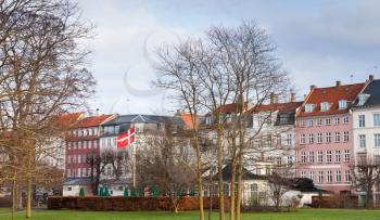 Cityscape of Copenhagen, Denmark. Bare trees and Danish national flag at winter day