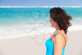 Young adult Caucasian woman in blue dress standing on the beach in Dominican Republic