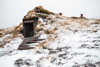 Abandoned cellar with broken door covered with snow. Iceland