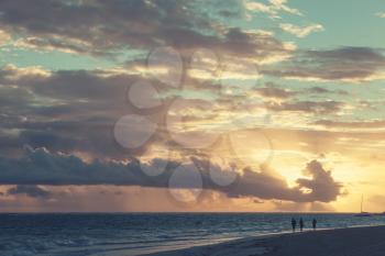 Sunrise over Atlantic ocean. Dominican republic, ordinary tourists walking along Punta Cana beach. Colorful tonal correction photo filter effect