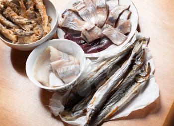 Assorted fish on wooden table. Roasted, marinated and salted smelt fish and herring fillet
