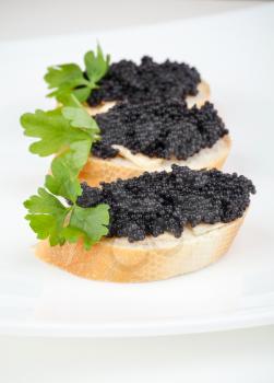 Small sandwiches with black caviar on white plate