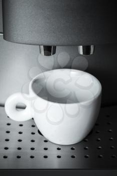 White ceramic cup stands in modern automatic coffee machine