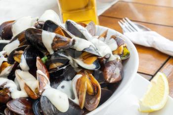 Plate full of mussels with garlic sauce on a table in restaurant 