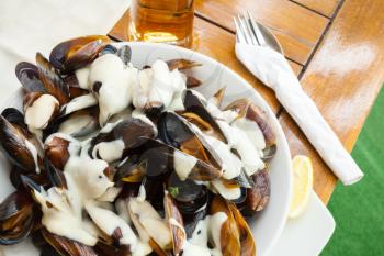 Plate full of mussels with garlic sauce on table in restaurant 