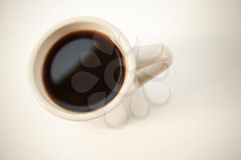 White cup full of black coffee stands on the table with soft shadow. Top view, soft shadow, vintage photo filter with old style effect