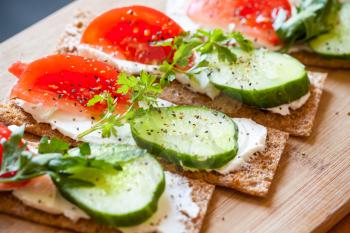 Healthy food theme. Sandwiches. Finnish rye crisp bread, soft cheese, cucumber, tomato, parsley and black pepper