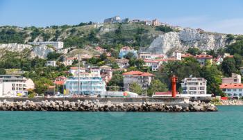 Balchik resort town. Entrance to the port, red lighthouse on the pier. Coast of the Black Sea, Varna region, Bulgaria