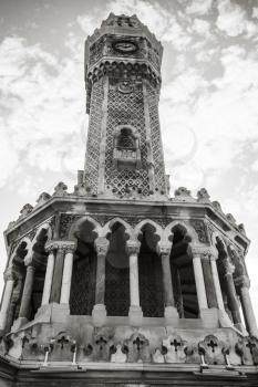 Historical clock tower under cloudy sky, it was built in 1901 and accepted as the official symbol of Izmir City, Turkey. Black and white photo